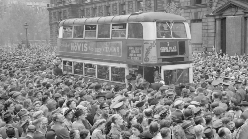 Frigjøringen blir annonsert av Winston Churchill, folk stoppet og lyttet i gatene slik at det ble umulig for busser å komme forbi.